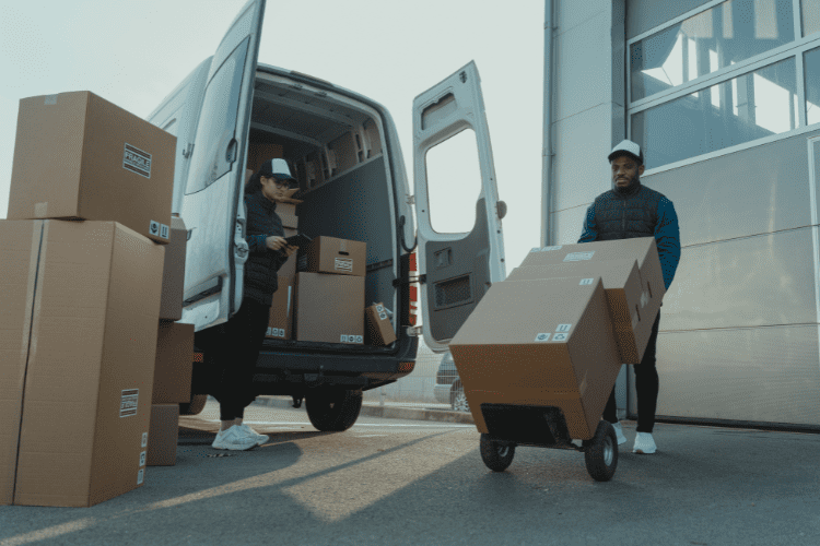 Two distribution workers unload a van